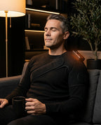 Man bär det uppvärmda axelbandaget från PyreFit i soffan